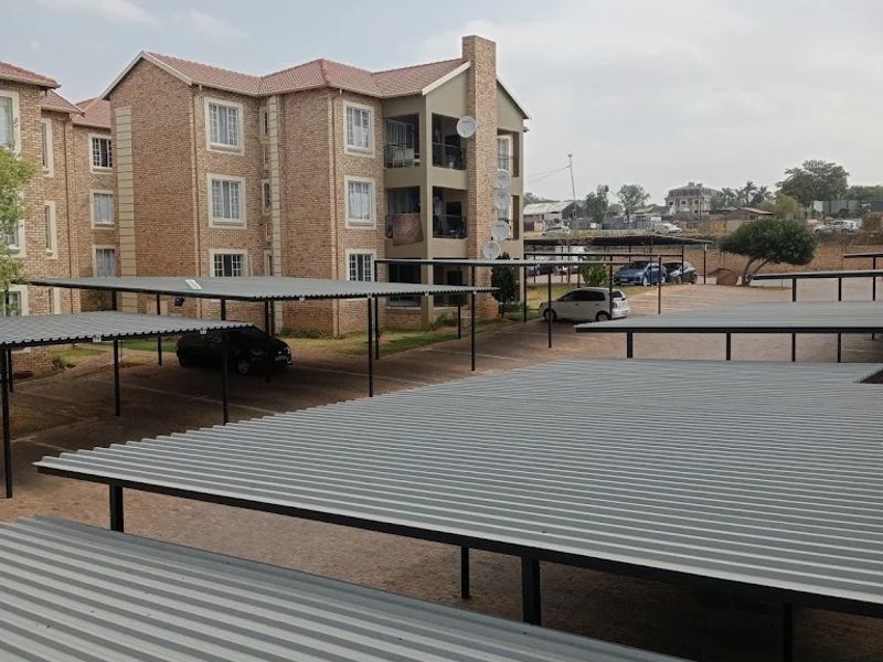 Exterior view of an apartment complex featuring multiple covered parking bays and brick building facades.
