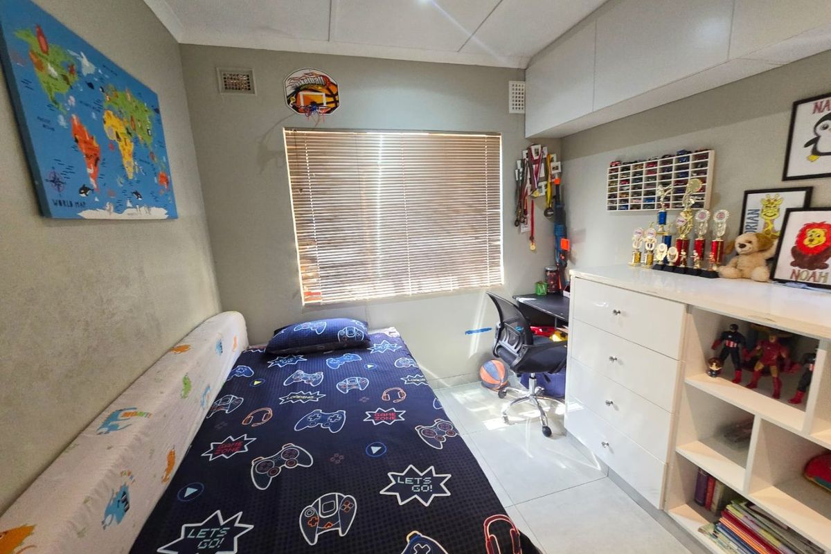 A well-maintained bedroom featuring tiled flooring, built-in cabinetry for storage, and venetian blinds, providing a functional and organized living space.