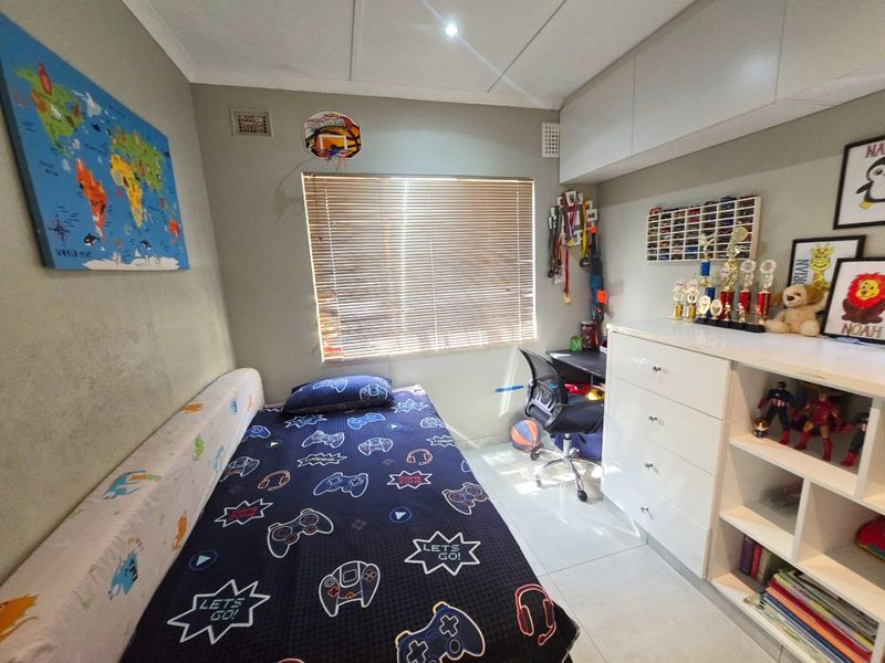 A well-maintained bedroom featuring tiled flooring, built-in cabinetry for storage, and venetian blinds, providing a functional and organized living space.