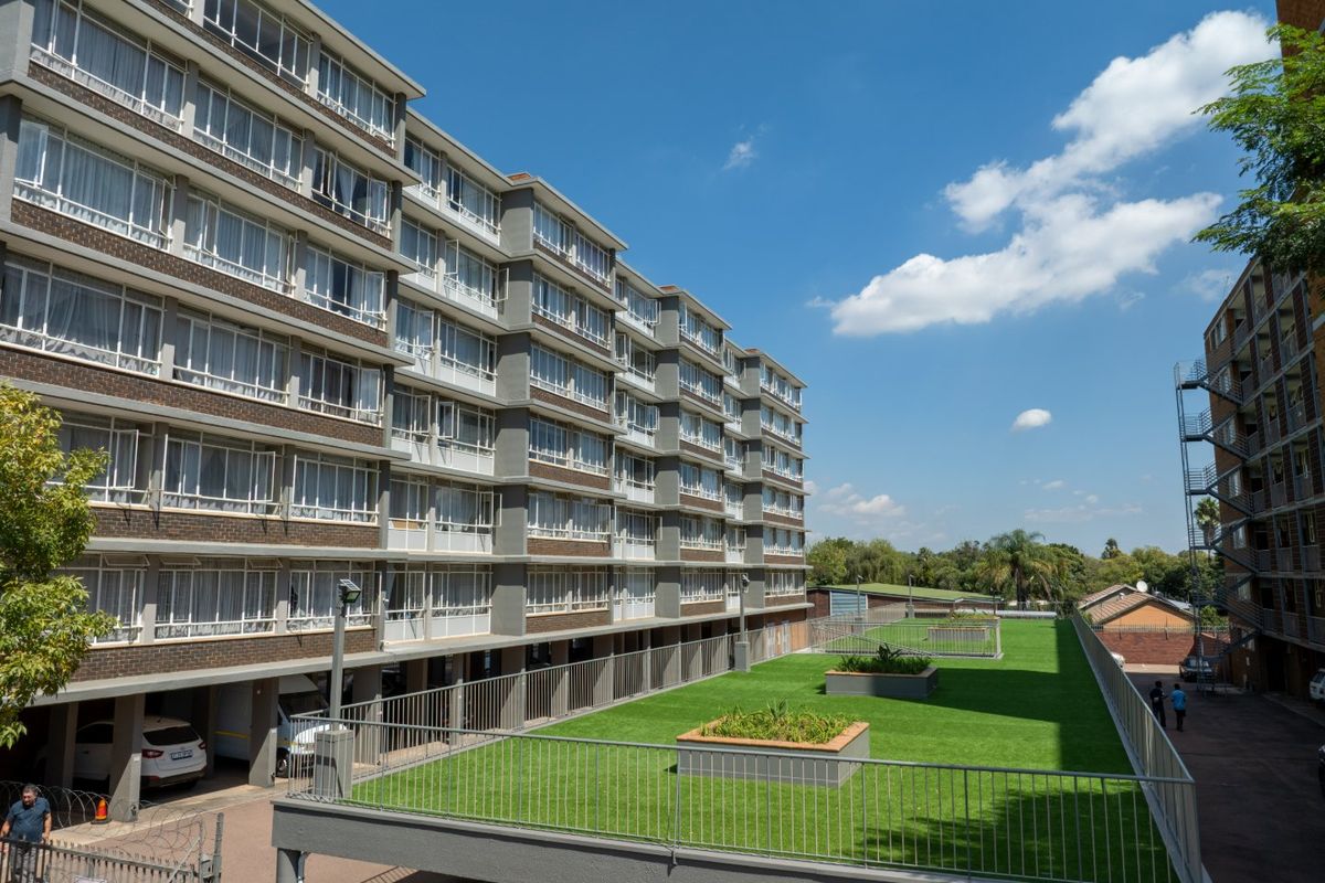 A view of a multi-story commercial building featuring a raised lawn terrace with metal balustrades and large window banks along the facade.