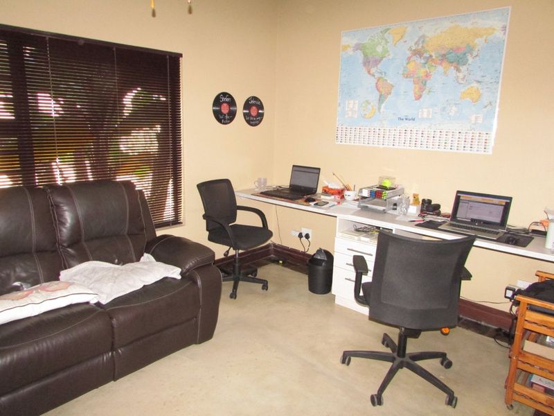 A functional home office space featuring a built-in desk, neutral wall finishes, and venetian blinds, providing a practical area for work or study.