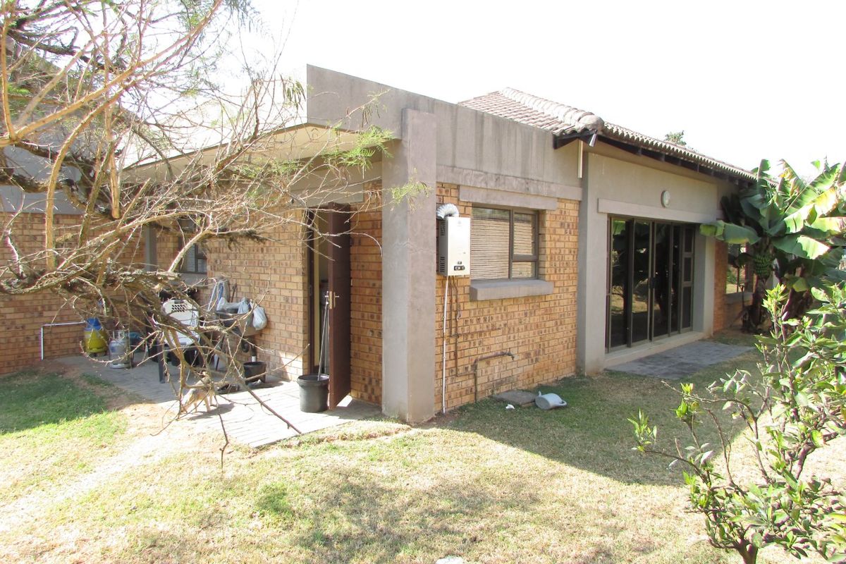 Rear view of the house featuring a face brick facade, concrete patio area, sliding glass doors, and an external gas geyser unit.