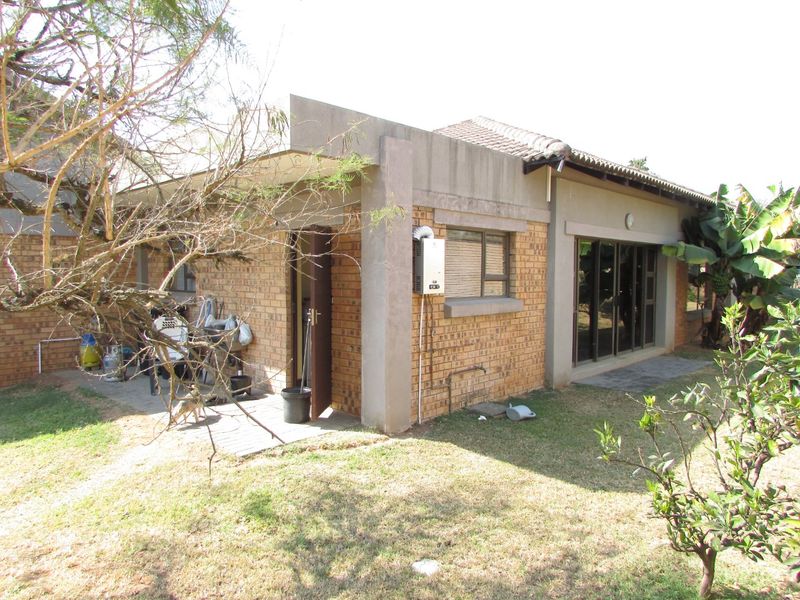 Rear view of the house featuring a face brick facade, concrete patio area, sliding glass doors, and an external gas geyser unit.