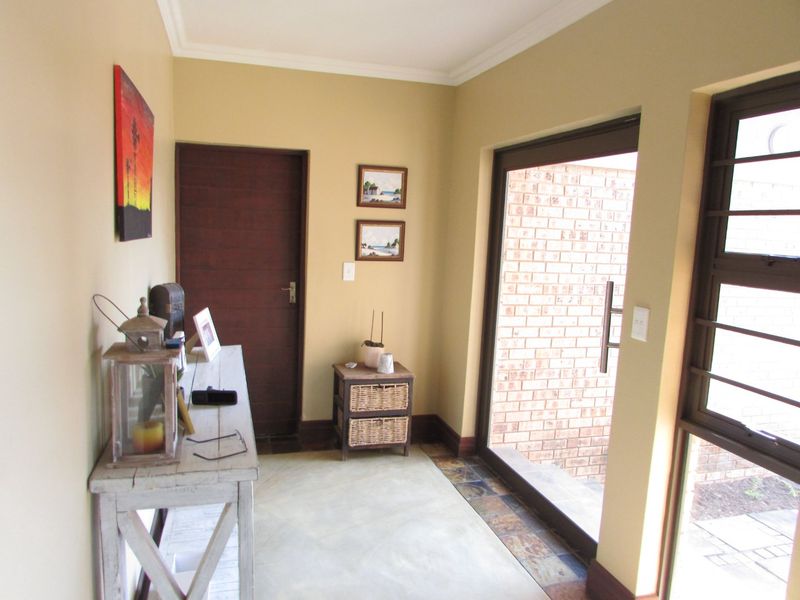 A bright entrance hall featuring tiled flooring, a sliding glass door providing outdoor access, and a solid timber door.