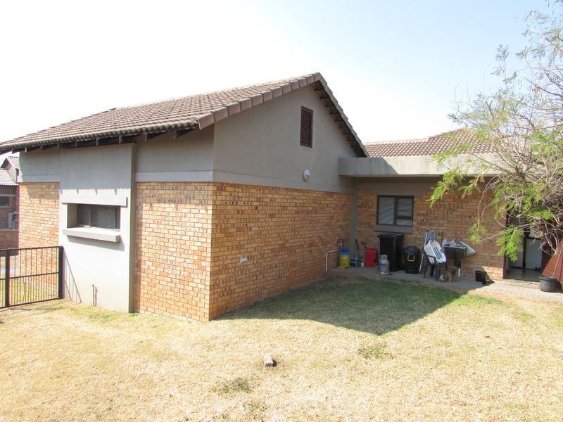 Rear view of the house featuring a combination of face brick and plastered walls with a tiled roof and small paved area.