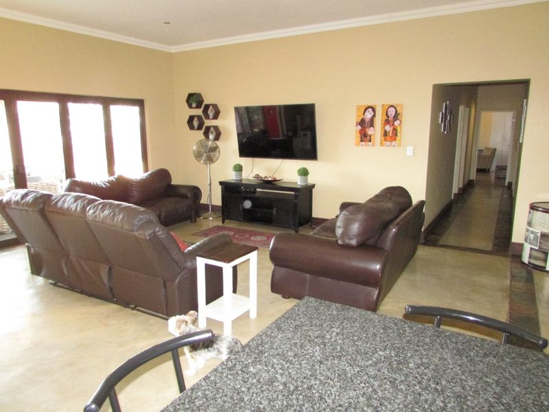 Spacious living room featuring polished concrete floors, neutral wall tones, and direct access to the hallway.