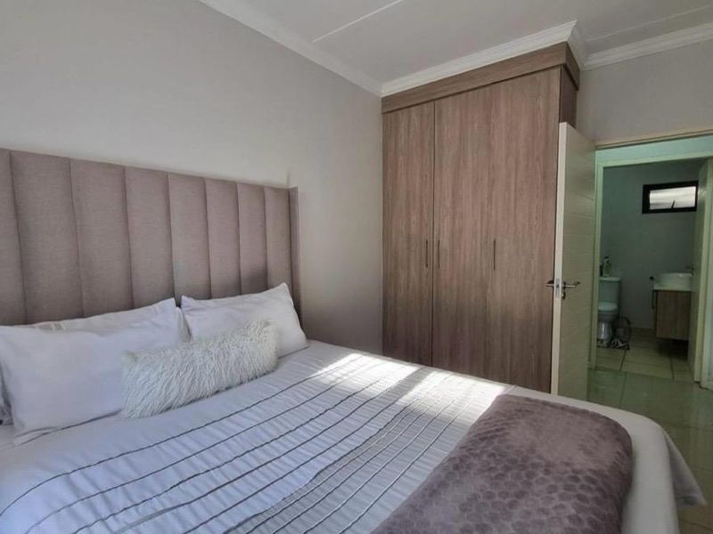 A well-maintained bedroom featuring a built-in wardrobe, neutral wall finishes, and direct access to an en-suite bathroom.