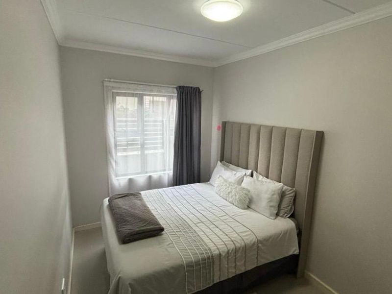 A well-maintained bedroom featuring neutral wall tones, crown molding, and a central ceiling light fixture.