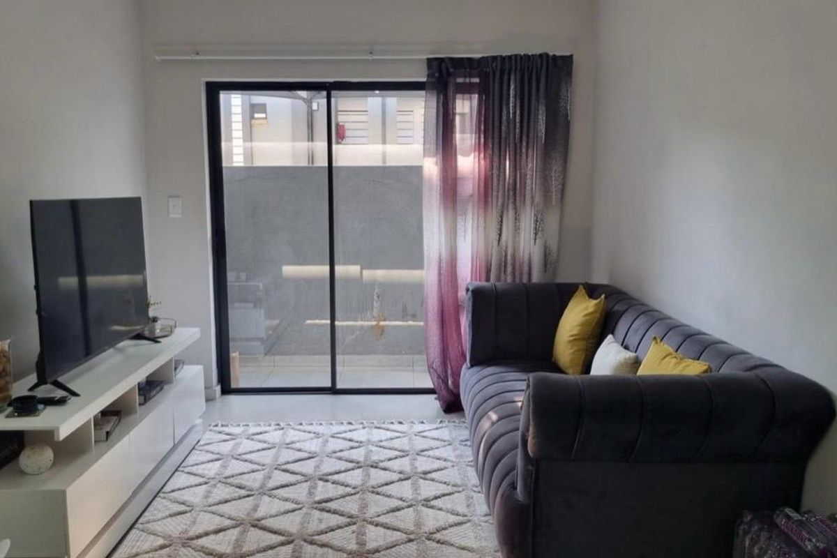 A cozy living room featuring tiled flooring and a large sliding glass door that provides access to the outdoor area.