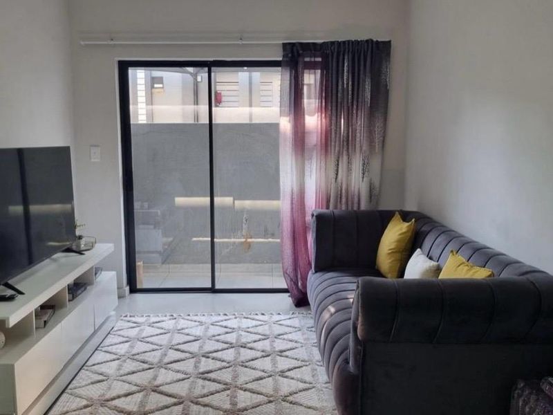 A cozy living room featuring tiled flooring and a large sliding glass door that provides access to the outdoor area.