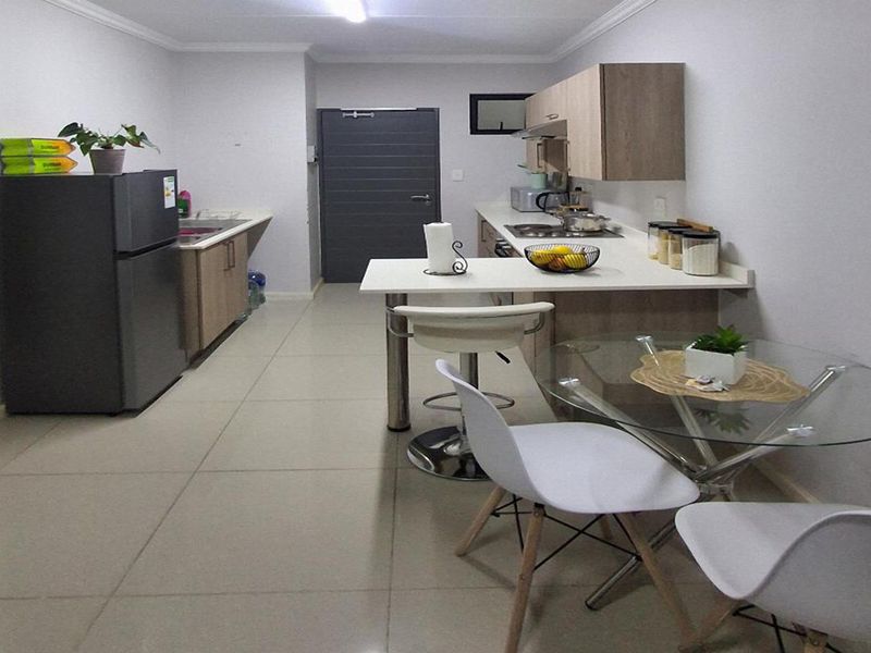 Open-plan kitchen and dining area featuring modern cabinetry, integrated hob, extractor fan, and neutral tiled flooring throughout.