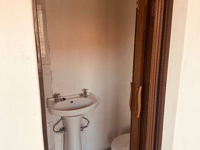 A small, dated bathroom featuring a pedestal basin and toilet, requiring cosmetic updates and refurbishment to improve its overall condition and appeal.