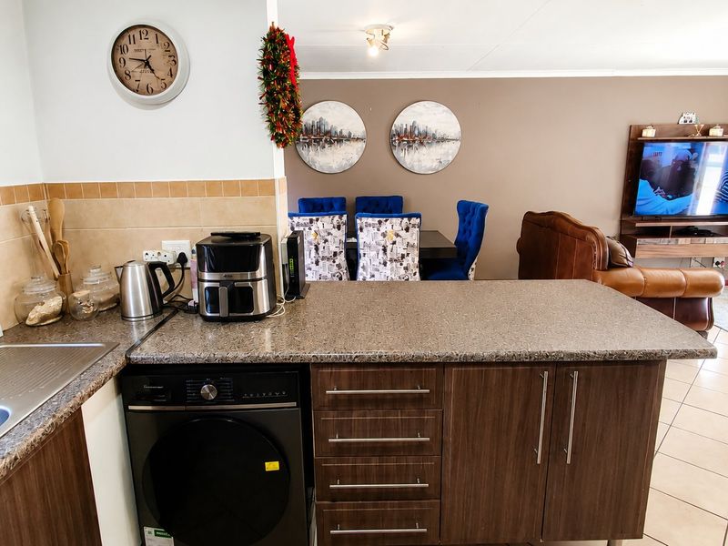 Open-plan living area featuring a kitchen with laminate cabinetry, granite-look countertops, and tiled flooring, seamlessly flowing into the dining and lounge space.