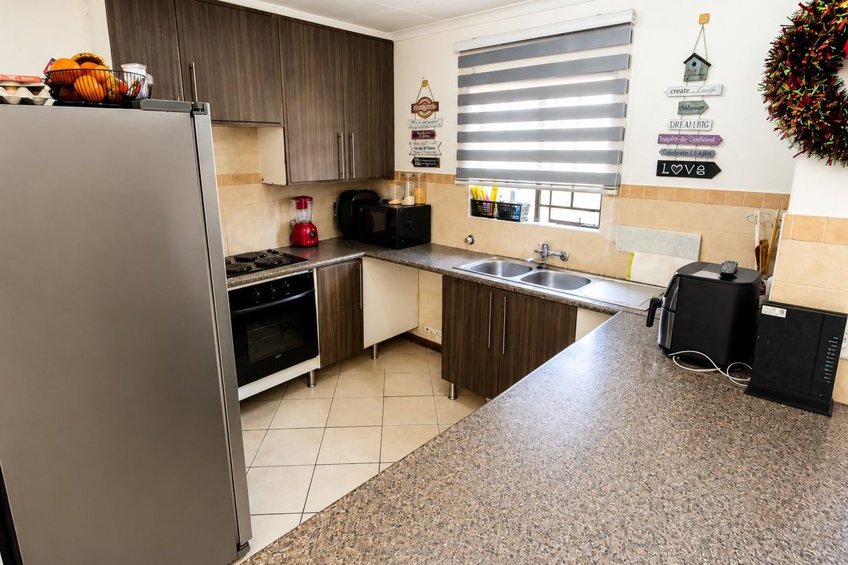 A functional kitchen featuring dark wood-look cabinetry, laminate countertops, a double bowl sink, and a built-in oven with hob.