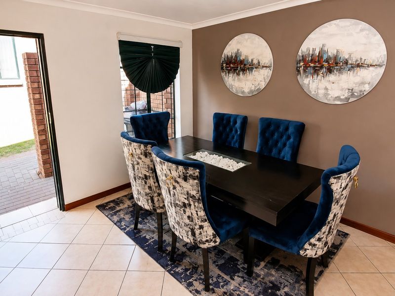 A well-lit dining room featuring tiled flooring and direct access to the exterior through a sliding door.