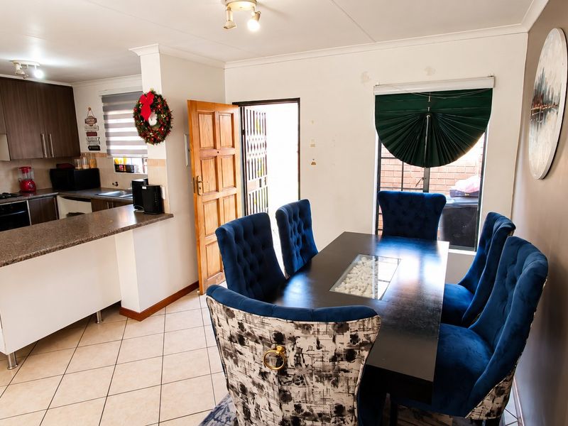 Open-plan kitchen and dining area featuring granite countertops, built-in cabinetry, and tiled flooring with direct access to the exterior.