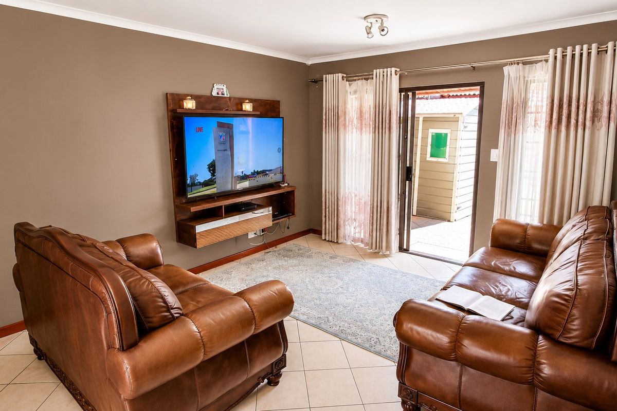 A comfortable living room featuring tiled flooring, a wall-mounted media console, and a sliding glass door providing direct access to the outdoor area.