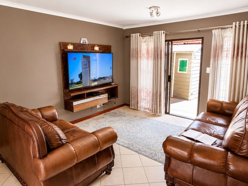 A comfortable living room featuring tiled flooring, a wall-mounted media console, and a sliding glass door providing direct access to the outdoor area.