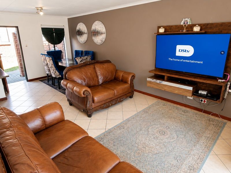 Open-plan living and dining area featuring tiled flooring and a built-in media console, creating a functional and connected space.