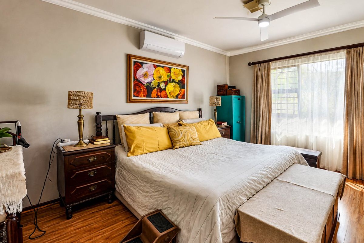 A well-maintained bedroom featuring laminate flooring, crown molding, a ceiling fan, and a wall-mounted split-system air conditioner.