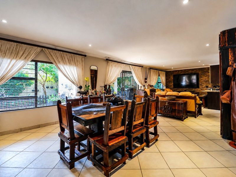 Spacious open-plan living and dining area featuring tiled floors, recessed lighting, and a stone feature wall, creating a warm and inviting atmosphere.