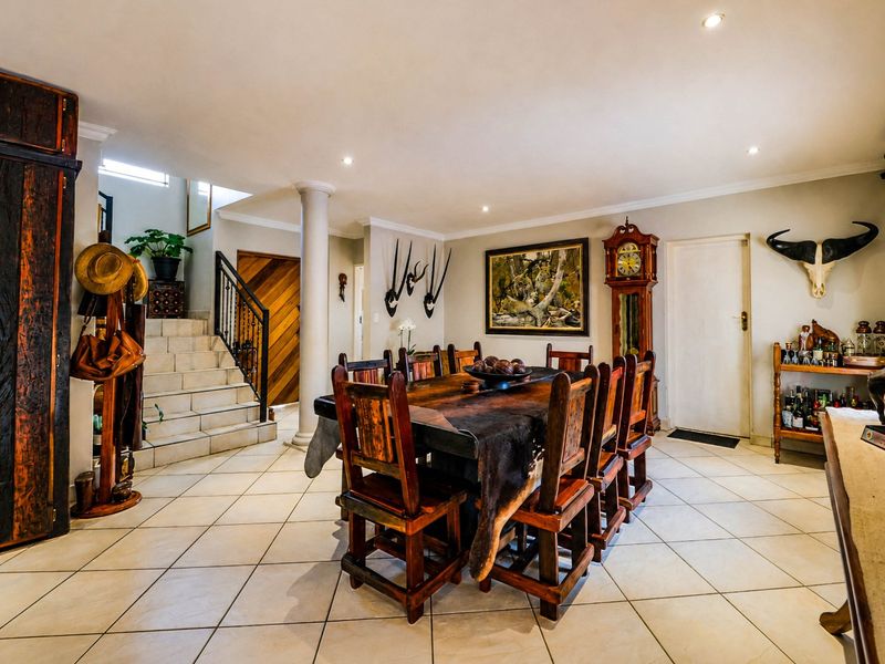 Spacious dining area featuring tiled flooring, recessed lighting, and an integrated staircase with a decorative wrought iron railing.
