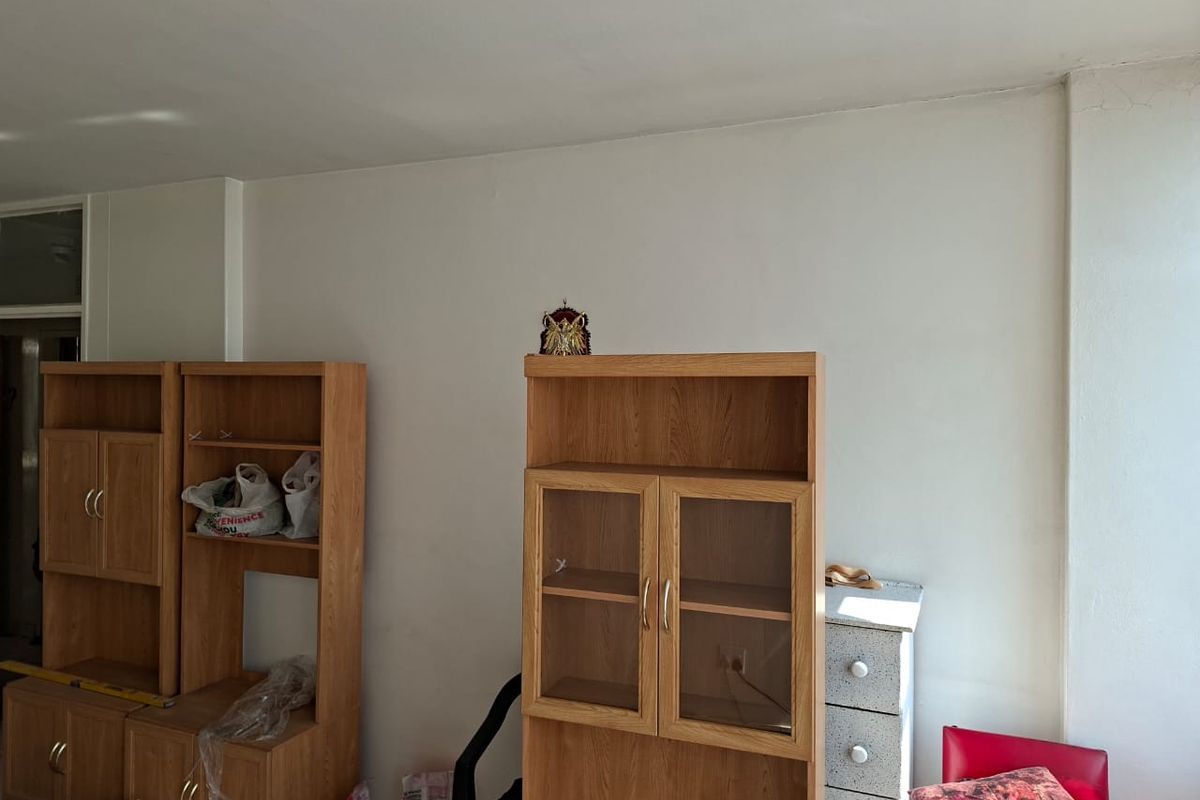 A living area featuring plain white walls and a ceiling with visible cracks, requiring cosmetic updates to improve the overall aesthetic.