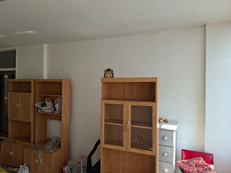 A living area featuring plain white walls and a ceiling with visible cracks, requiring cosmetic updates to improve the overall aesthetic.