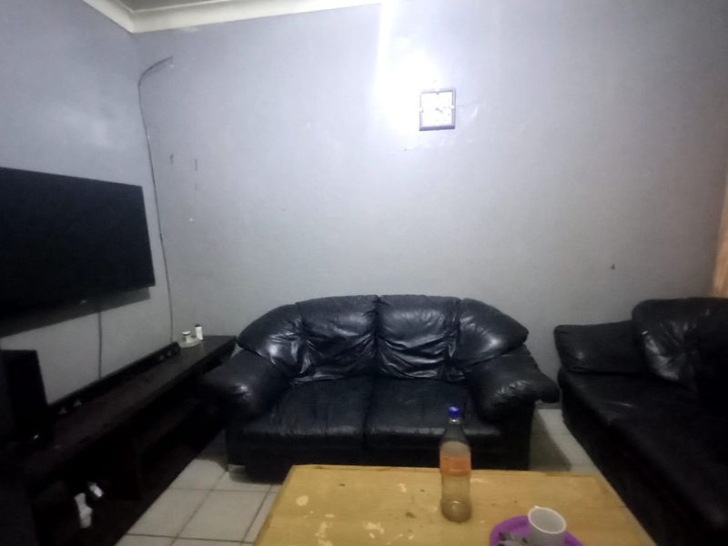 A living room featuring tiled flooring and coved ceilings, currently requiring cosmetic updates to improve the overall finish and presentation.