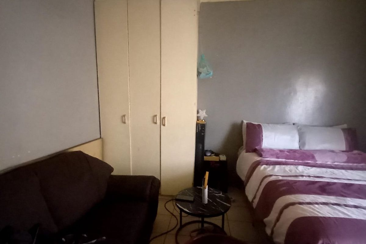 A bedroom featuring built-in wardrobes and tiled flooring, requiring cosmetic updates to improve the overall aesthetic and condition of the space.