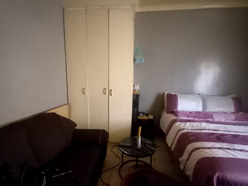 A bedroom featuring built-in wardrobes and tiled flooring, requiring cosmetic updates to improve the overall aesthetic and condition of the space.
