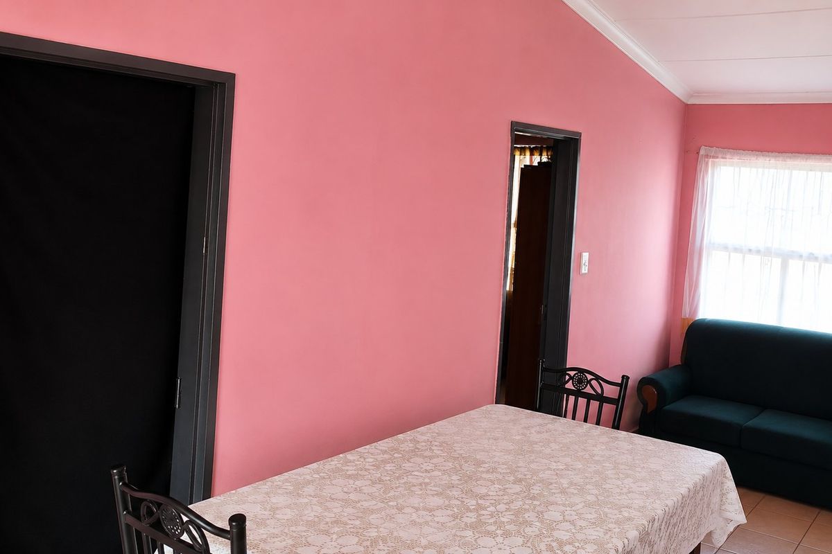 A living area featuring tiled flooring and cove cornicing, finished with bright pink wall paint.