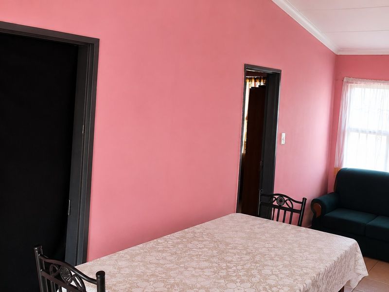 A living area featuring tiled flooring and cove cornicing, finished with bright pink wall paint.