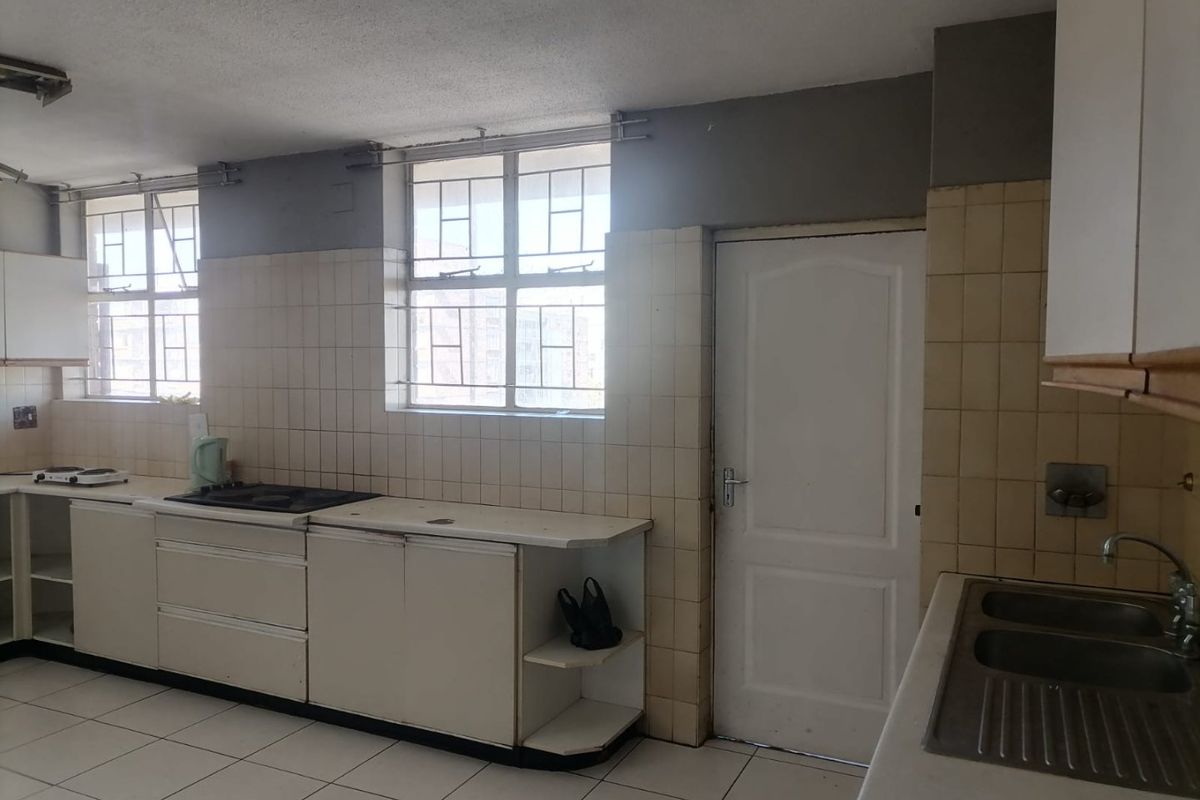 A dated kitchen featuring built-in cabinetry, tiled splashbacks, a double bowl sink, and a built-in hob, offering a functional layout ready for modernization.