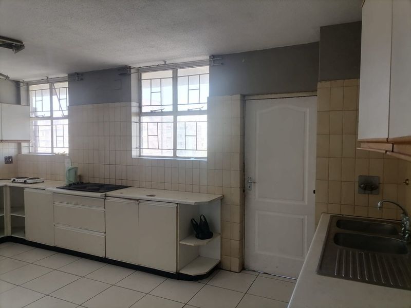 A dated kitchen featuring built-in cabinetry, tiled splashbacks, a double bowl sink, and a built-in hob, offering a functional layout ready for modernization.