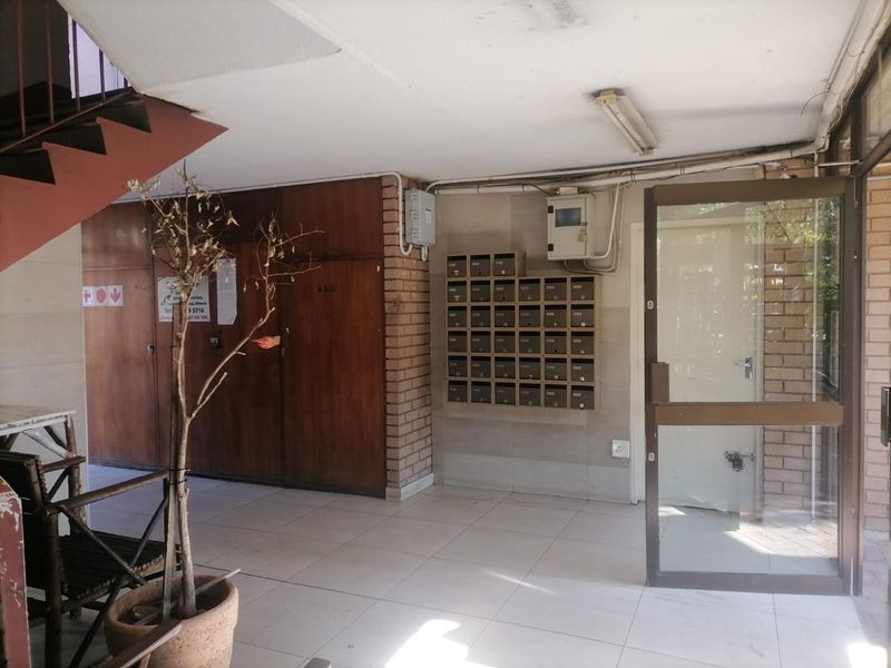 Communal apartment building entrance lobby featuring tiled flooring, a staircase, and a bank of built-in mailboxes.