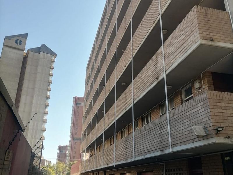 Exterior view of a multi-story apartment building featuring brick facade, private balconies, and ground-level garage access.