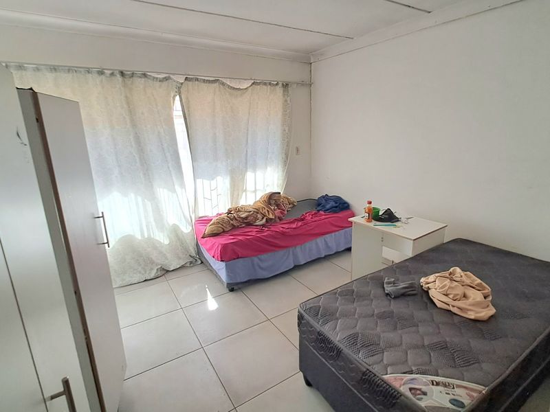 A bedroom featuring tiled flooring and curtain rails, requiring some ceiling maintenance to improve the overall finish.