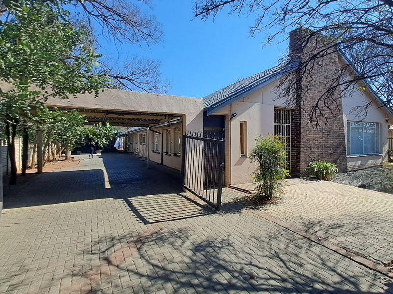 Front exterior view of the house featuring a paved driveway, attached carport, and a prominent brick chimney facade.