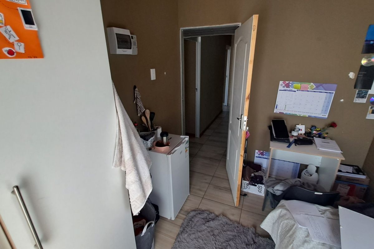 A bedroom featuring tiled flooring and an internal door, providing access to the hallway area.