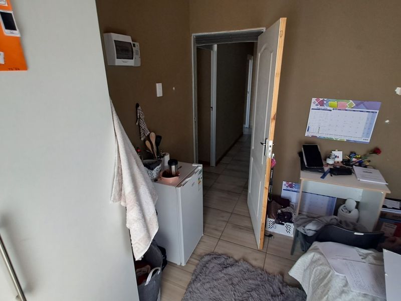 A bedroom featuring tiled flooring and an internal door, providing access to the hallway area.