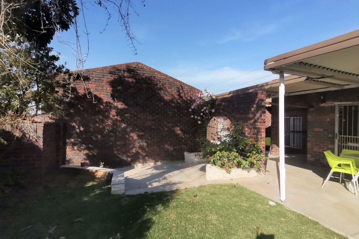 A private rear garden featuring a brick boundary wall, built-in planter boxes, and a covered patio area with concrete flooring.