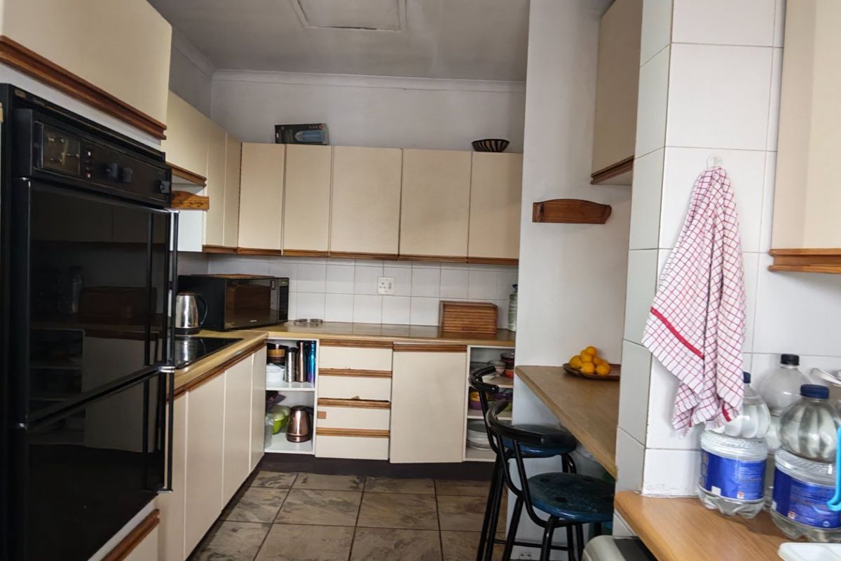 A functional kitchen featuring built-in cabinetry, laminate countertops, tiled backsplash, and a breakfast nook, offering potential for modernization and aesthetic updates.