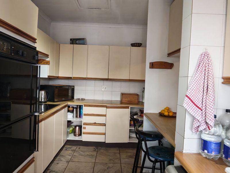 A functional kitchen featuring built-in cabinetry, laminate countertops, tiled backsplash, and a breakfast nook, offering potential for modernization and aesthetic updates.
