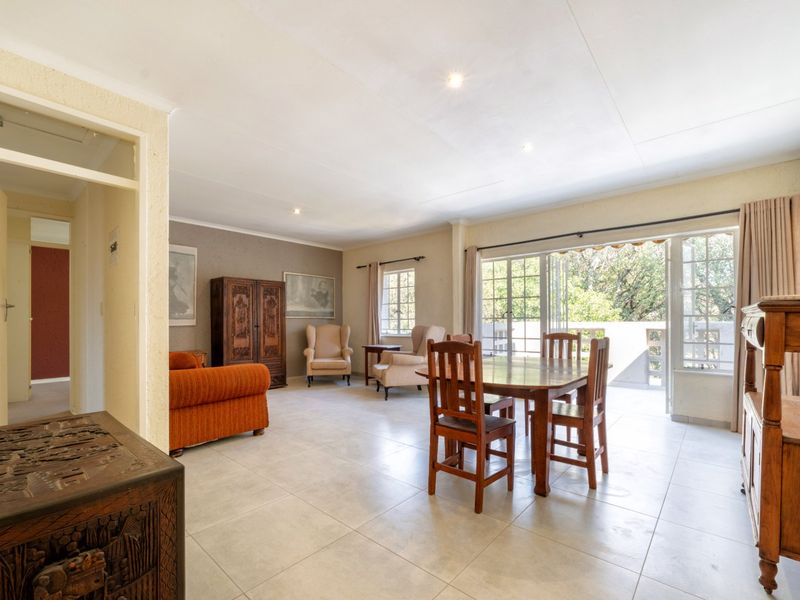 Spacious open-plan living and dining area featuring neutral tiled flooring, recessed lighting, and large glass doors opening onto an outdoor balcony.