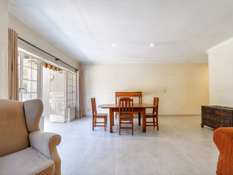 Spacious living and dining area featuring neutral tiled flooring, recessed lighting, and direct access to an outdoor patio through a sliding glass door.
