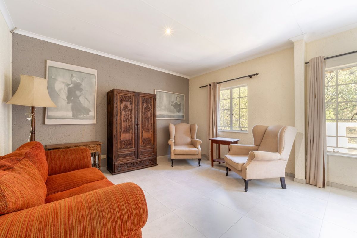 A well-lit living room featuring neutral tiled flooring, textured accent walls, and large windows that provide natural light.