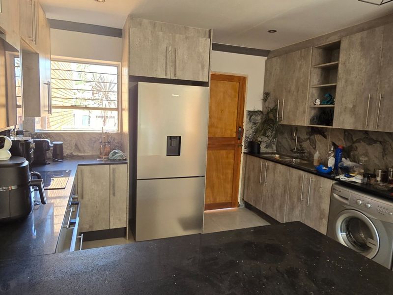Modern kitchen featuring contemporary grey cabinetry, dark stone countertops, integrated sink, and recessed lighting, offering a functional and stylish workspace.