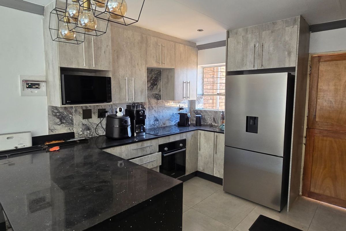 Modern kitchen featuring stone countertops, built-in cabinetry, integrated oven and microwave, and tiled flooring with a functional layout.