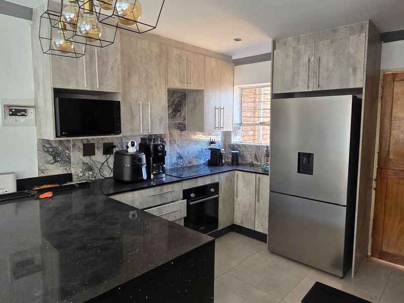 Modern kitchen featuring stone countertops, built-in cabinetry, integrated oven and microwave, and tiled flooring with a functional layout.